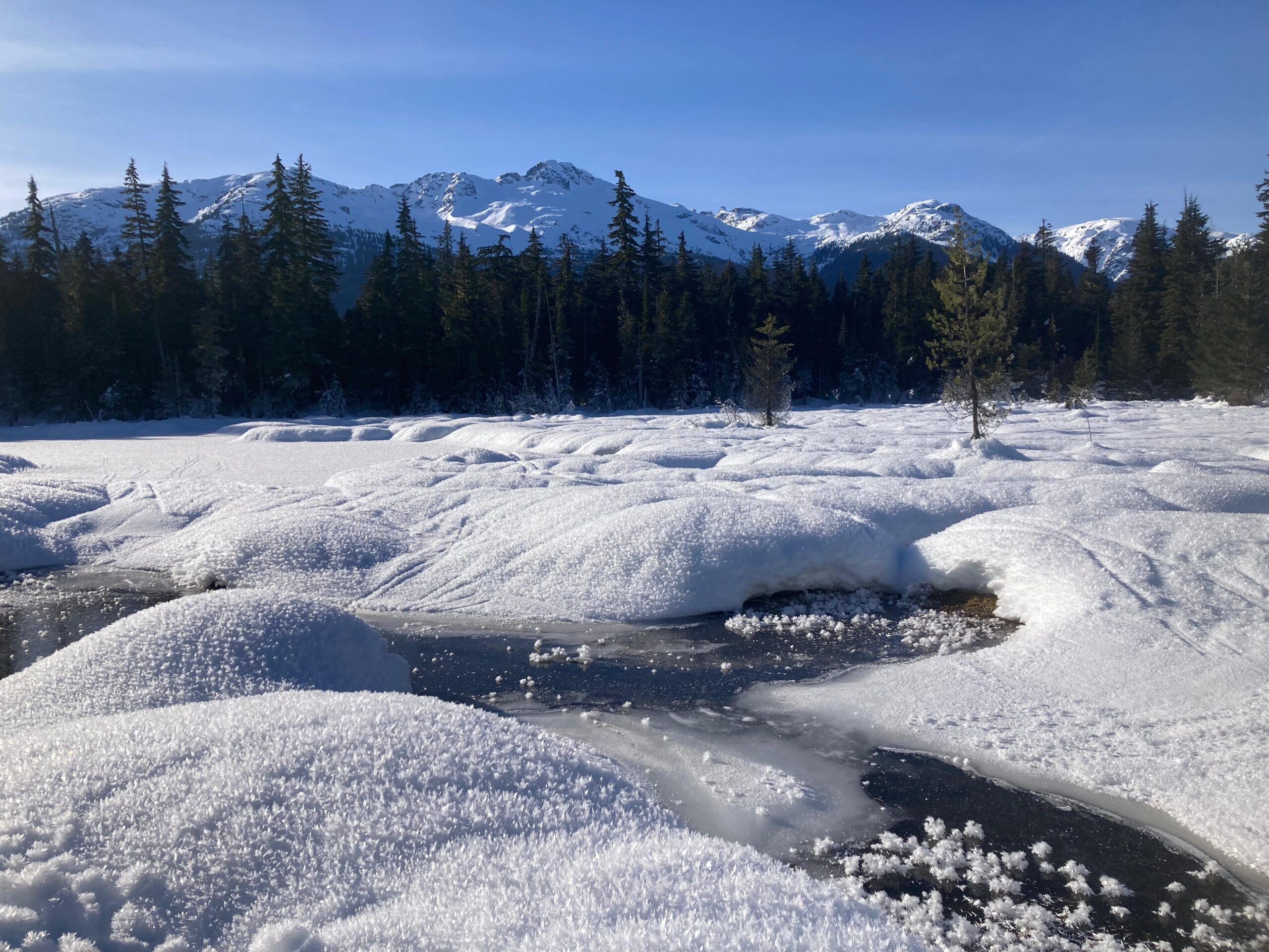 Rivière gelée devant des pics enneigés. Photo par Aurore Lacas.